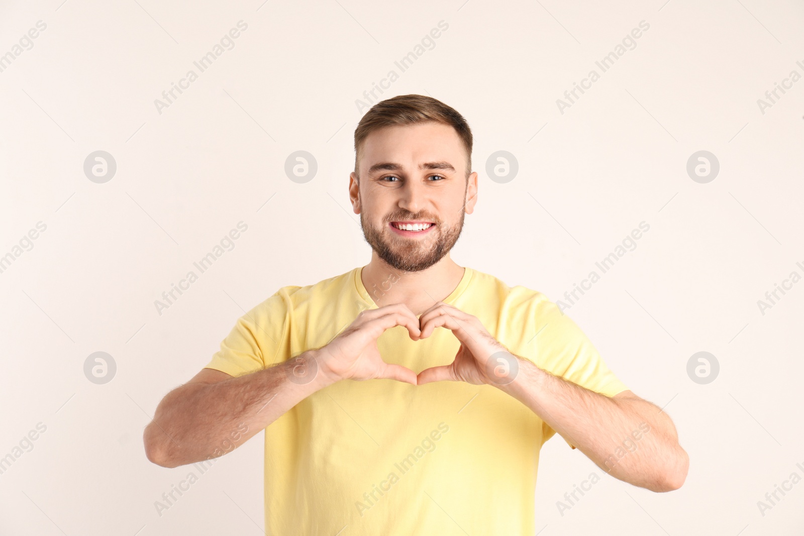 Photo of Young man making heart with his hands on white background