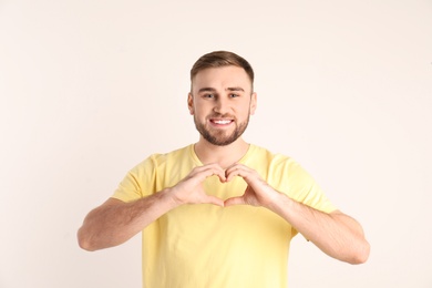 Young man making heart with his hands on white background