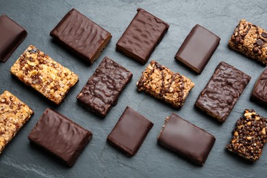Photo of Different tasty protein bars on black table, flat lay