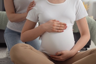 Photo of Doula taking care of pregnant woman indoors, closeup. Preparation for child birth