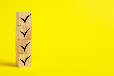 Stacked wooden cubes with check marks on yellow background. Space for text