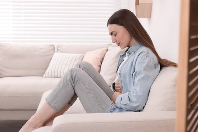 Photo of Young woman suffering from stomach pain at home