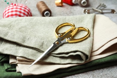 Scissors, spools of threads and sewing tools on light textured table, closeup