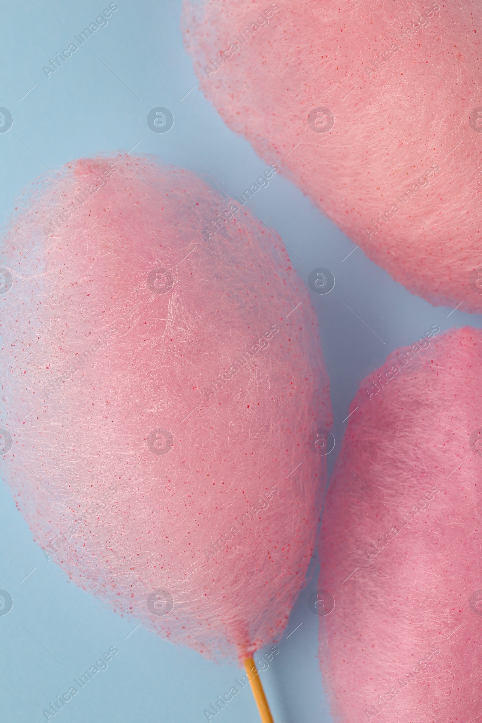 Photo of Sweet pink cotton candies on light blue background, flat lay