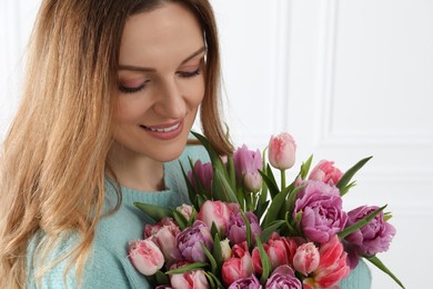 Photo of Happy young woman with bouquet of beautiful tulips indoors