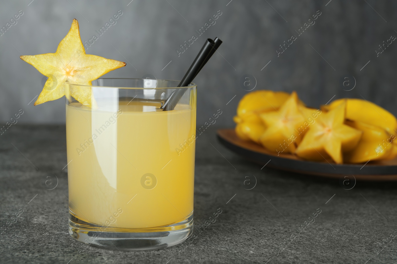 Photo of Delicious carambola juice on grey table. Space for text