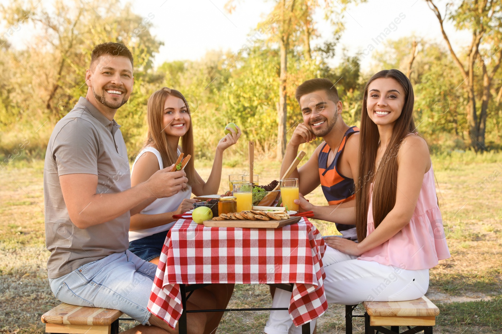 Photo of Happy young people having picnic at table in park