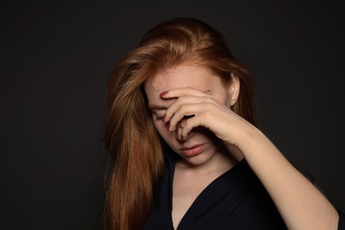 Photo of Young woman covering face against dark background