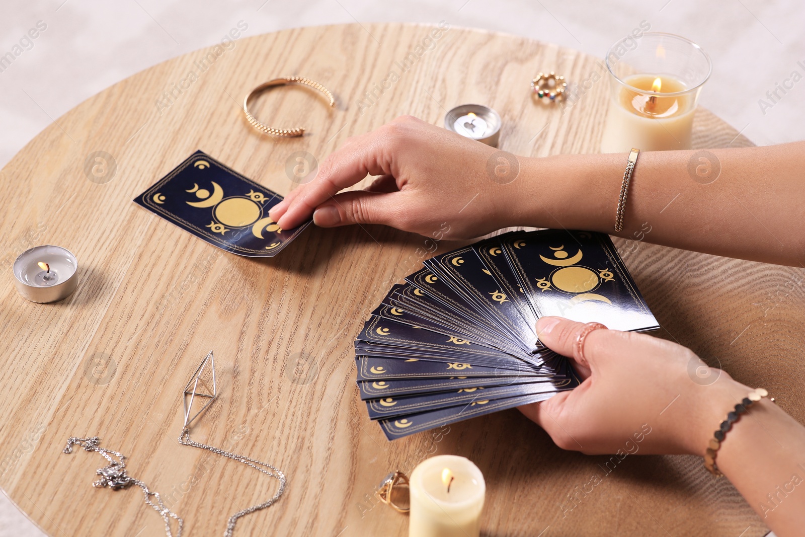 Photo of Soothsayer predicting future with tarot cards at table indoors, closeup