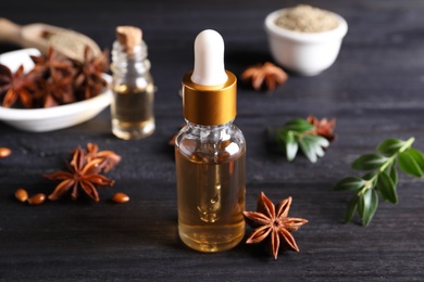 Photo of Anise essential oil and spice on dark wooden table