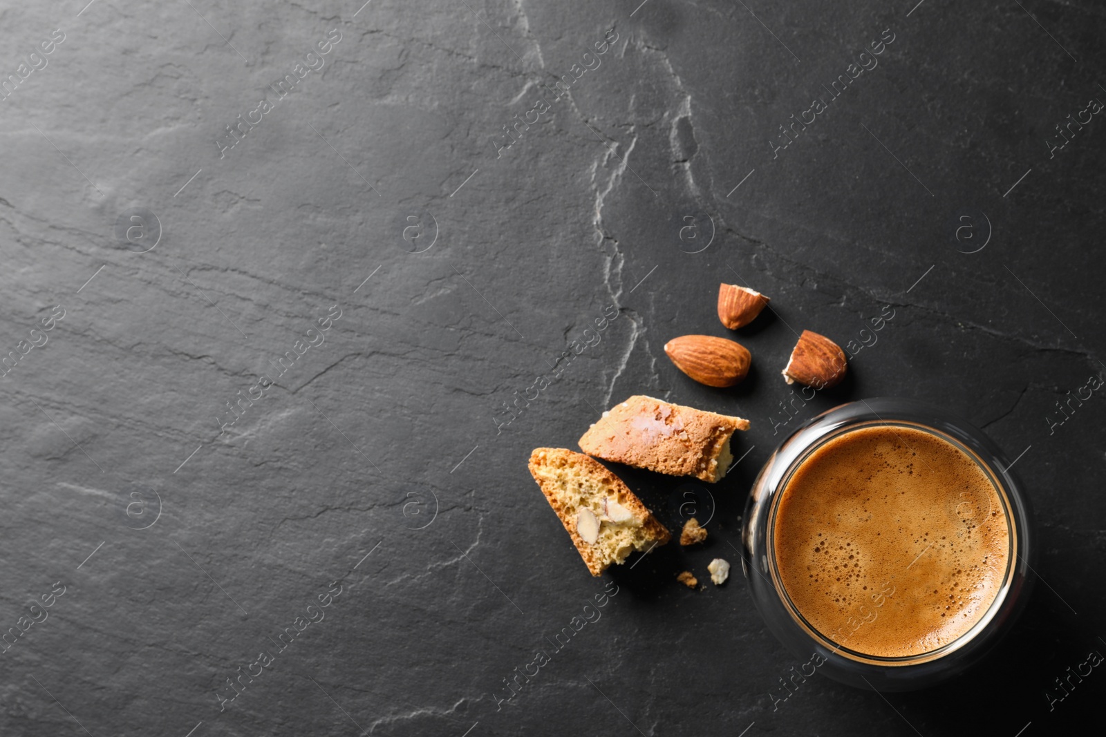 Photo of Tasty cantucci and cup of aromatic coffee on black table, flat lay with space for text. Traditional Italian almond biscuits