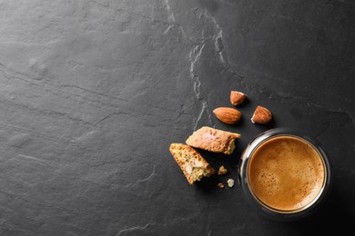 Tasty cantucci and cup of aromatic coffee on black table, flat lay with space for text. Traditional Italian almond biscuits