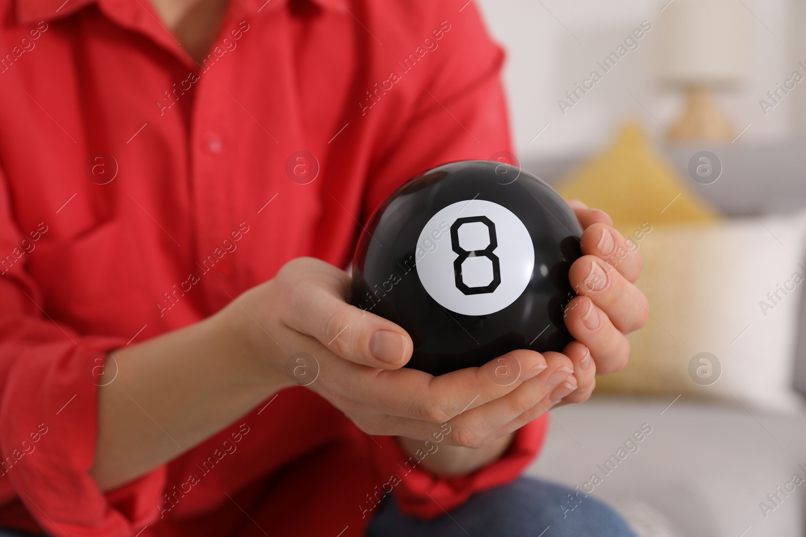 Photo of Woman holding magic eight ball indoors, closeup