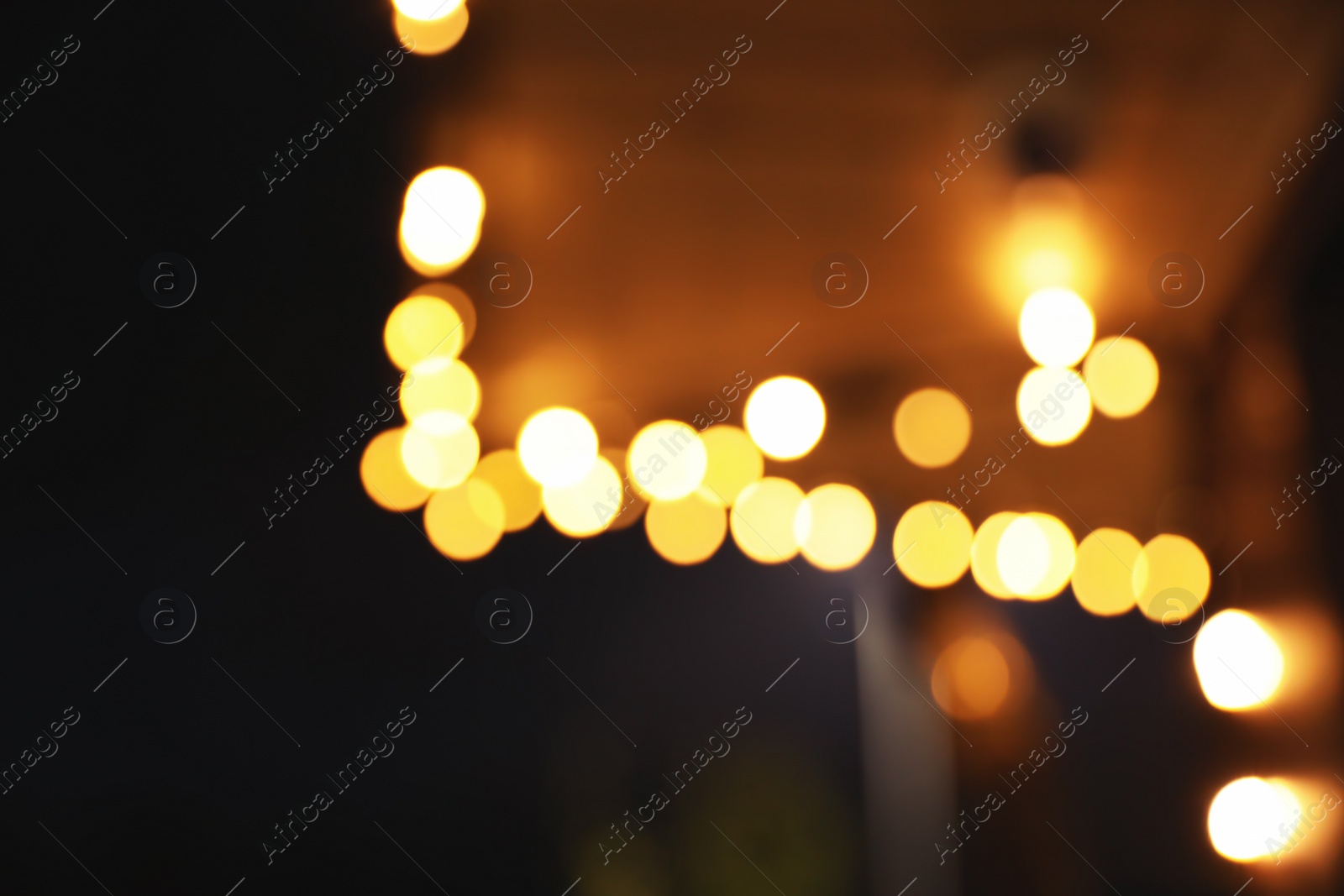 Photo of Blurred view of glowing lights on wooden column, closeup