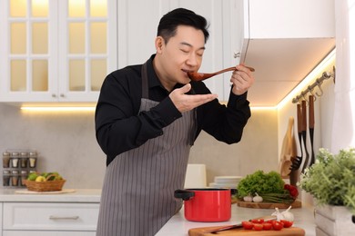 Man tasting dish after cooking in kitchen