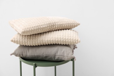 Soft pillows on side table near beige wall