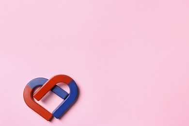 Photo of Red and blue horseshoe magnets on pink background, flat lay. Space for text