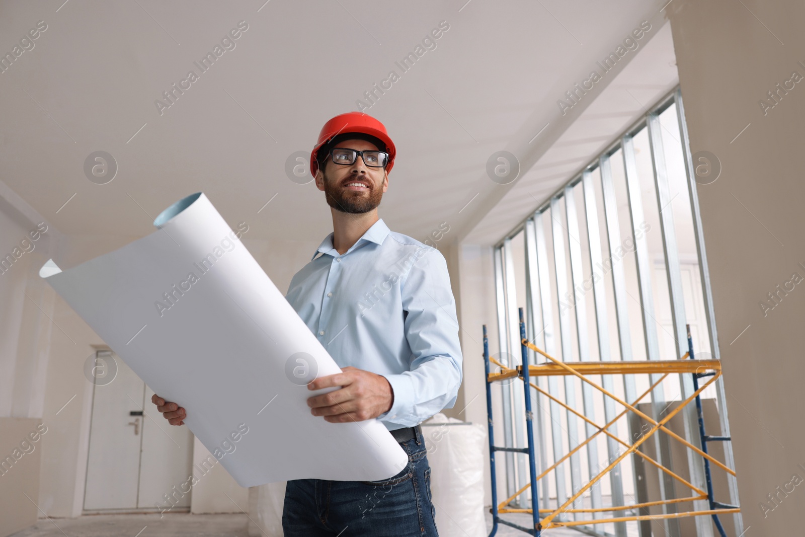 Photo of Professional engineer in hard hat with draft indoors, low angle view