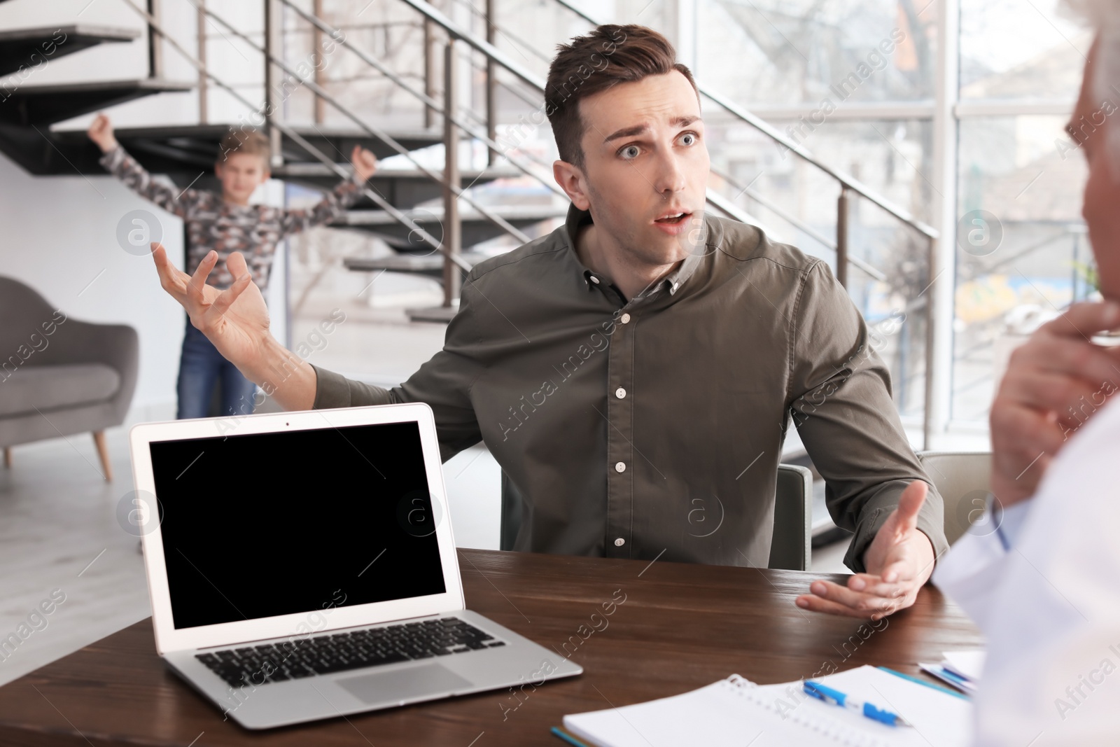 Photo of Young man complaining about mischievous son at child psychologist office