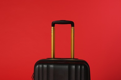 Stylish black suitcase with handle on color background