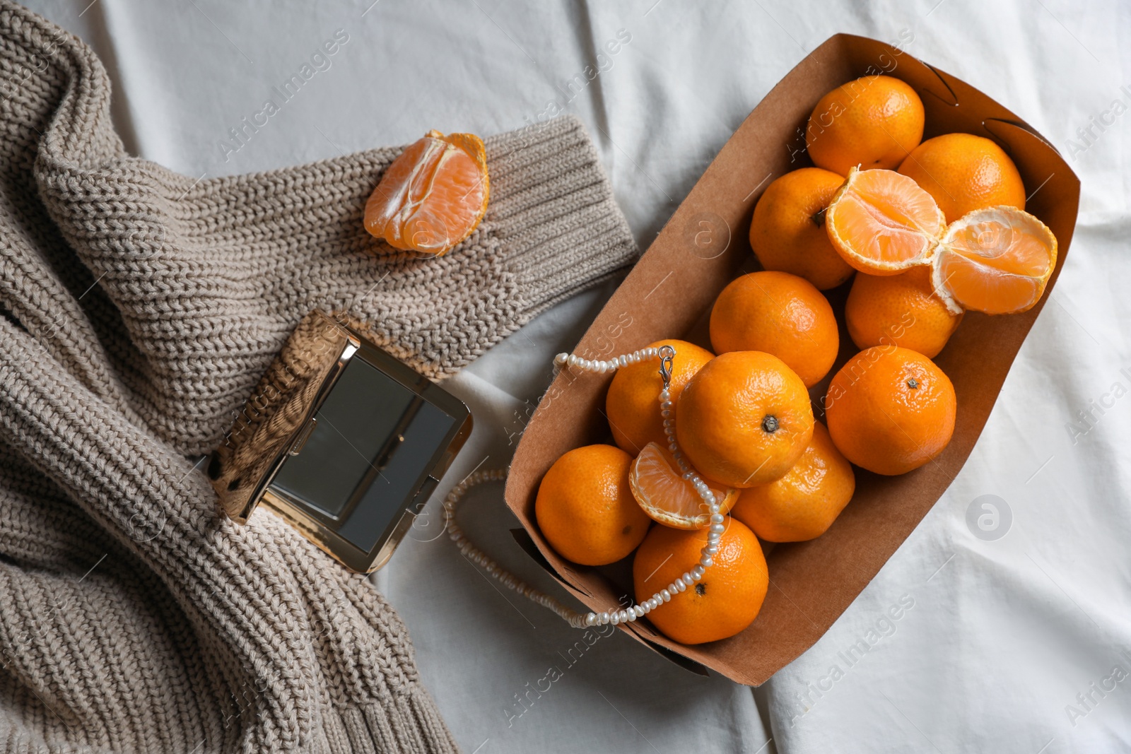 Photo of Paper box with fresh ripe tangerines and decor on white cloth, flat lay