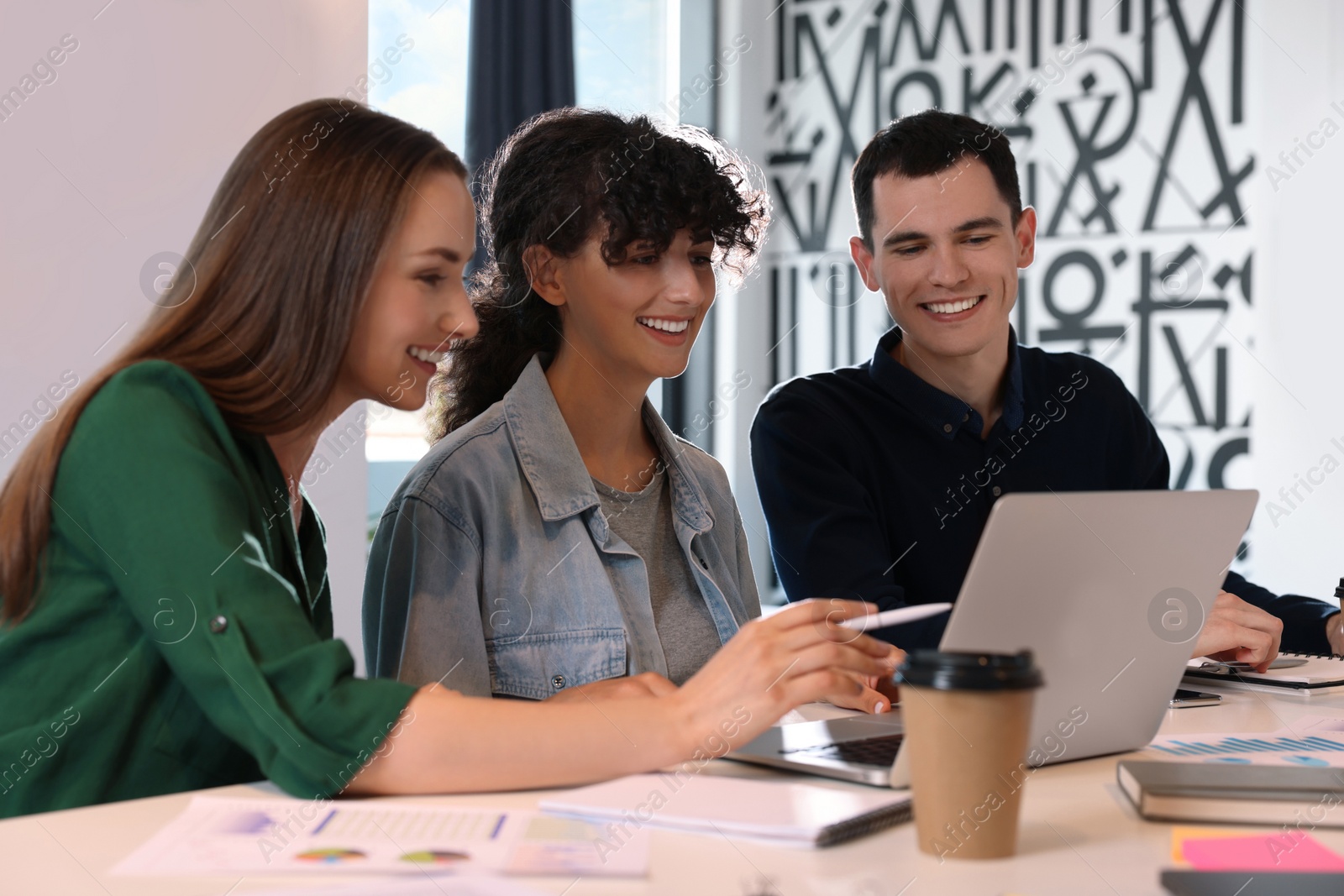 Photo of Team of employees working together at table in office. Startup project