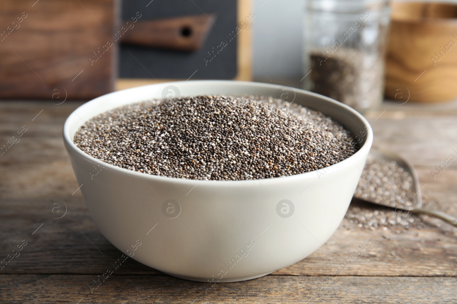 Photo of Bowl with chia seeds on wooden table against blurred background