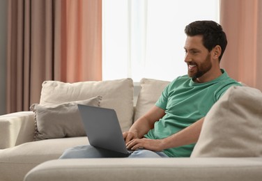 Photo of Man using laptop on sofa at home