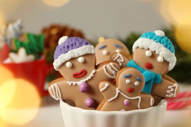 Photo of Delicious homemade Christmas cookies in bowl against blurred festive lights, closeup