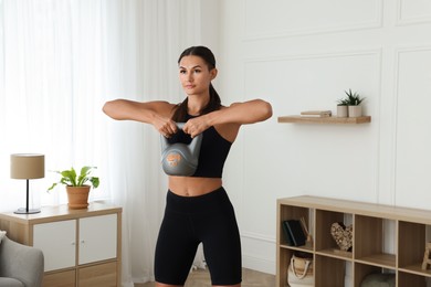 Young woman exercising with kettlebell at home