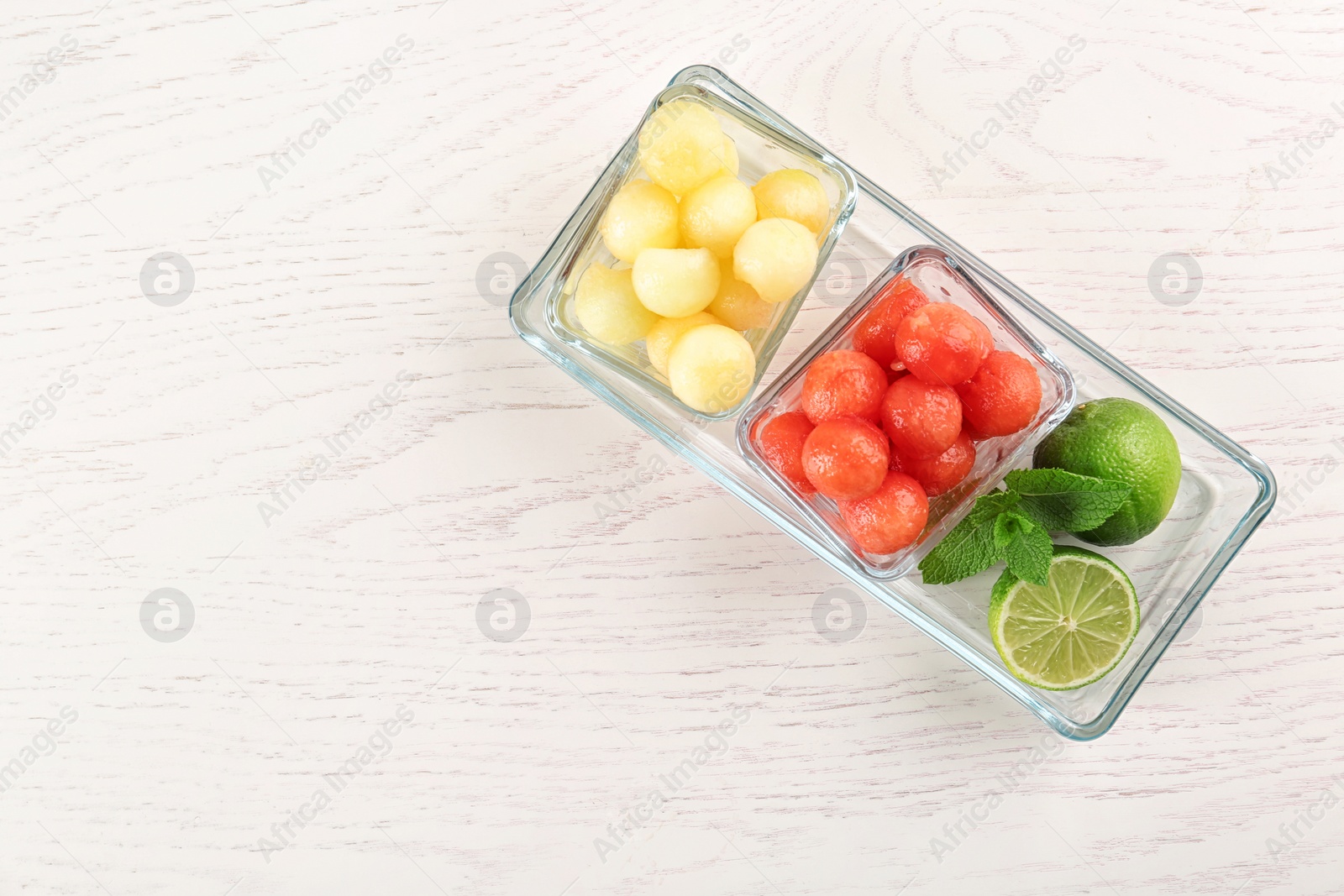 Photo of Melon and watermelon balls with lime served on white wooden table, top view. Space for text