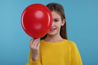 Photo of Happy girl with red balloon on light blue background