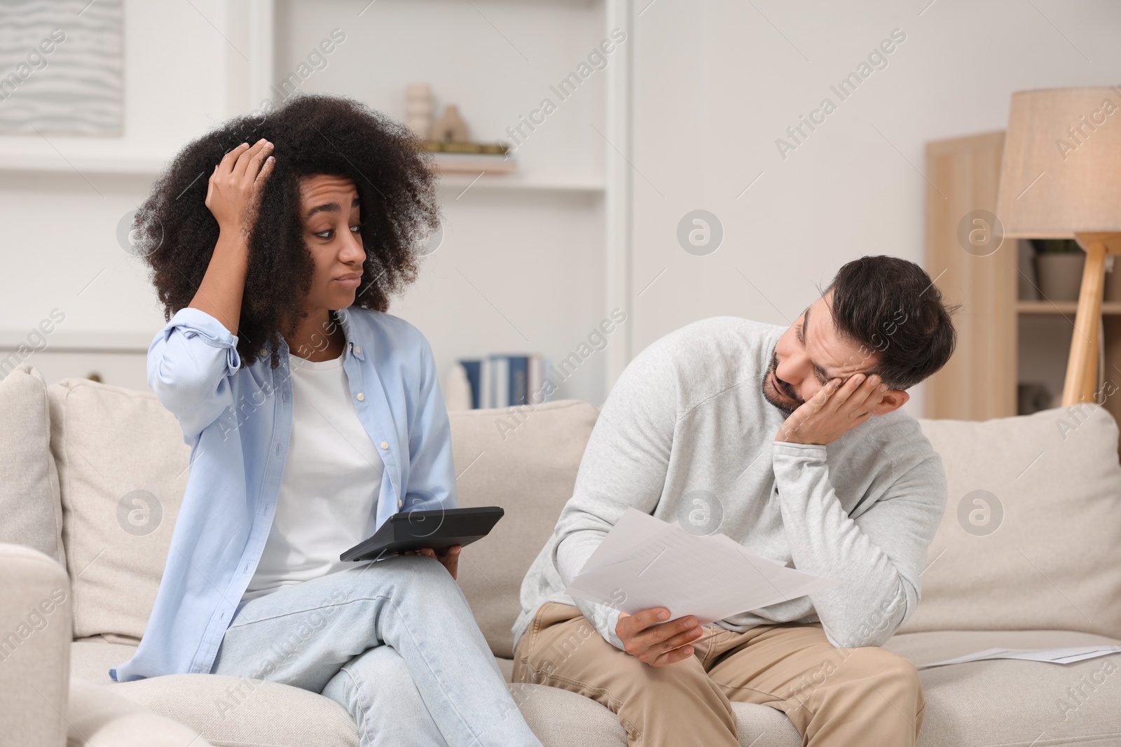 Photo of Confused couple with debt notifications and calculator planning budget at home. Financial problem