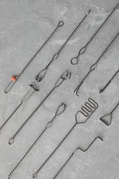 Photo of Set of different logopedic probes on marble table, flat lay. Speech therapist's tools