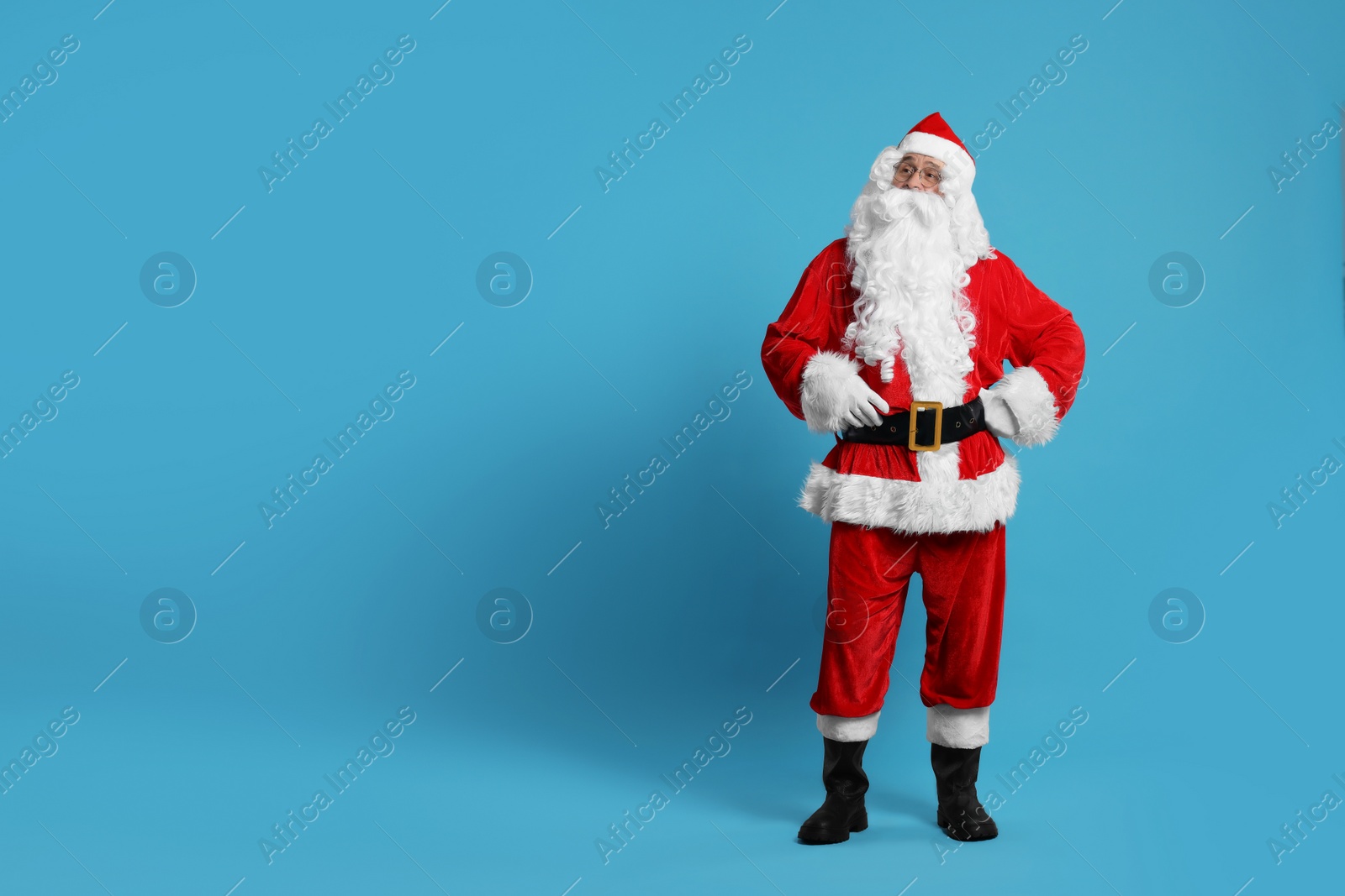 Photo of Merry Christmas. Santa Claus posing on light blue background, space for text