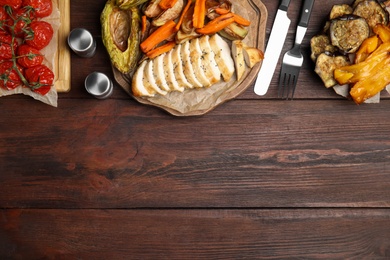 Tasty cooked chicken fillet and vegetables served on wooden table, flat lay with space for text. Healthy meals from air fryer