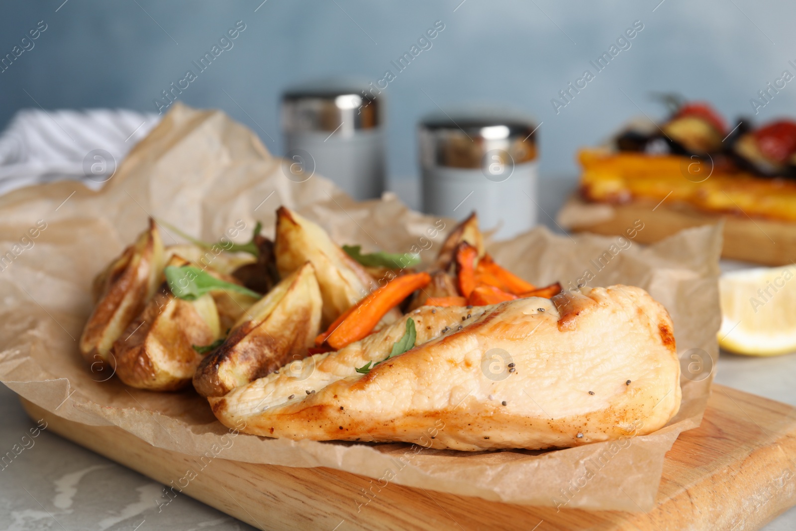 Photo of Delicious cooked chicken and vegetables on grey marble table, closeup. Healthy meals from air fryer