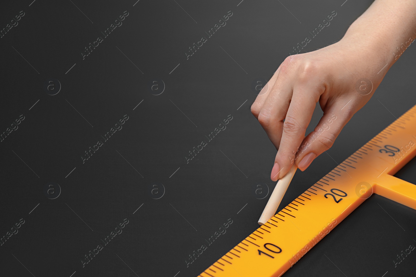 Photo of Woman drawing with chalk and triangle ruler on blackboard, closeup. Space for text