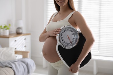 Young pregnant woman with scales at home, closeup