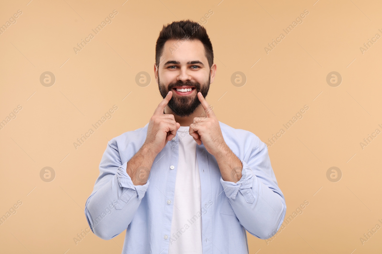 Photo of Man showing his clean teeth and smiling on beige background