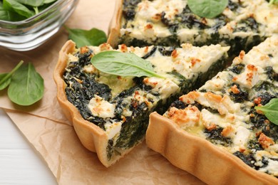 Photo of Delicious homemade spinach quiche on parchment paper, closeup