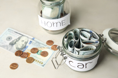 Photo of Glass jars with money and tags on white table