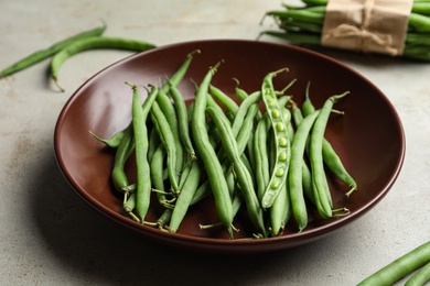 Photo of Fresh green beans in bowl on light grey table