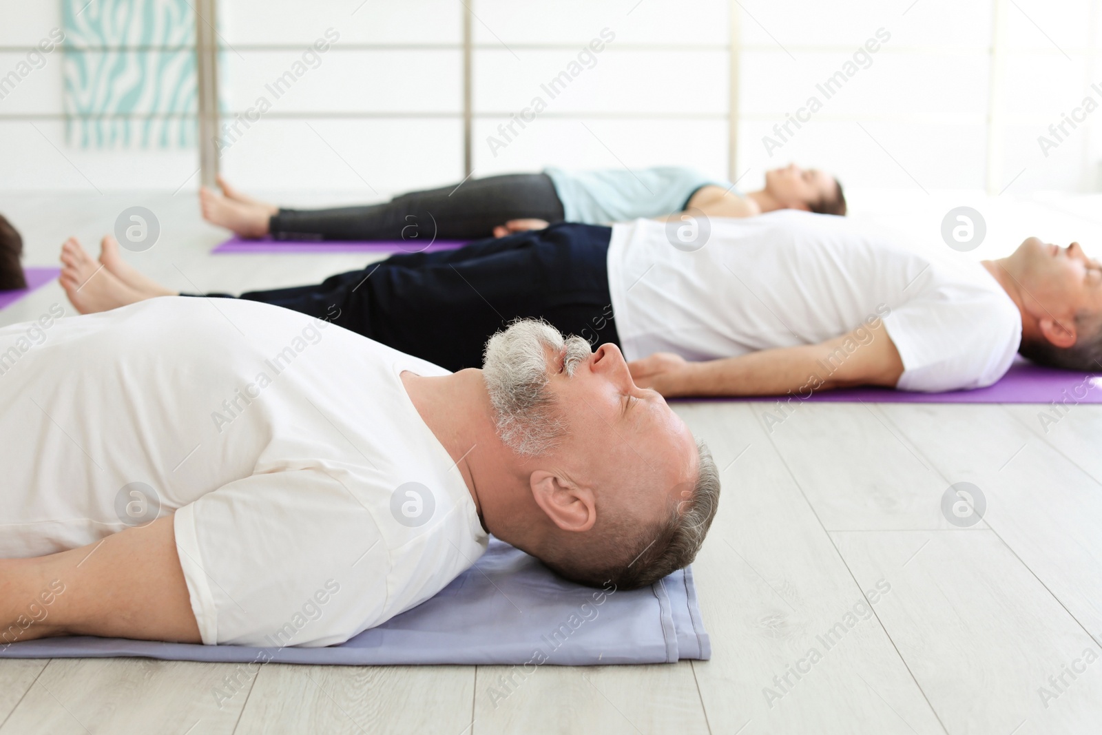 Photo of Group of people in sportswear practicing yoga indoors