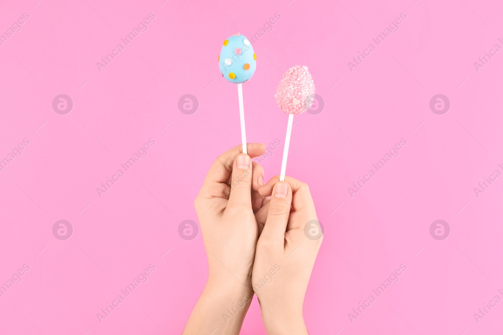 Photo of Woman with delicious cake pops on pink background, closeup. Easter holiday