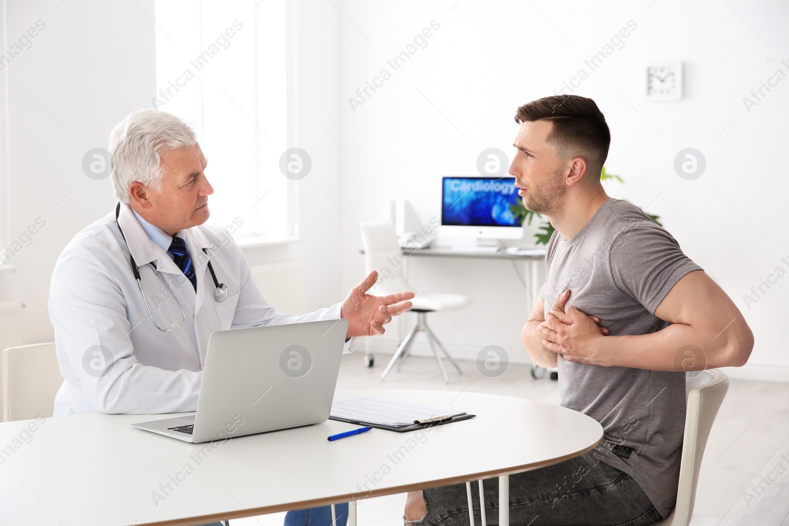 Photo of Male doctor working with patient in clinic. Cardiology consultation