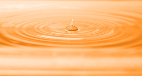 Splash of water with drops as background, closeup. Toned in orange