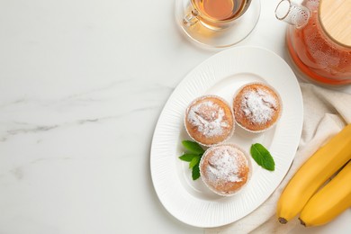 Flat lay composition with homemade banana muffins and tea on white marble table. Space for text