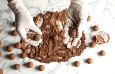 Woman with tasty chocolate truffles at table, top view