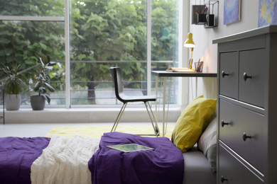 Photo of Modern teenager's room interior with comfortable bed, workplace and stylish design elements